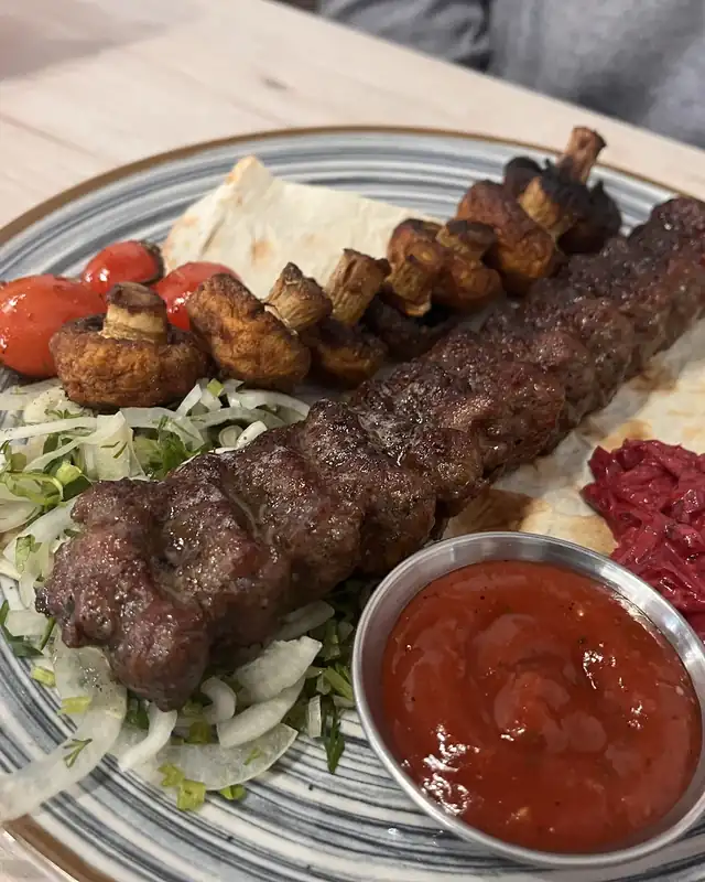 Lula kebab z grilla na talerzu z warzywami i sosem
